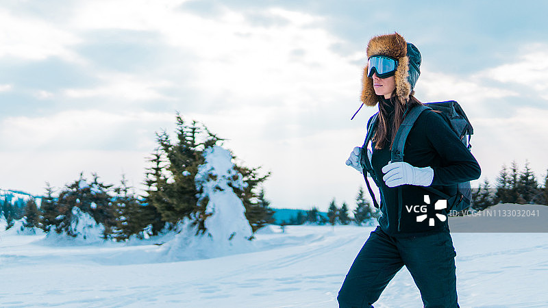 背着背包穿过雪林的滑雪女人图片素材