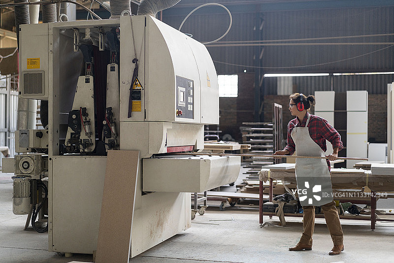 中年女工匠将木头插入机器图片素材