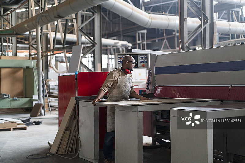 在工作台上拿着木板的秃头木匠图片素材