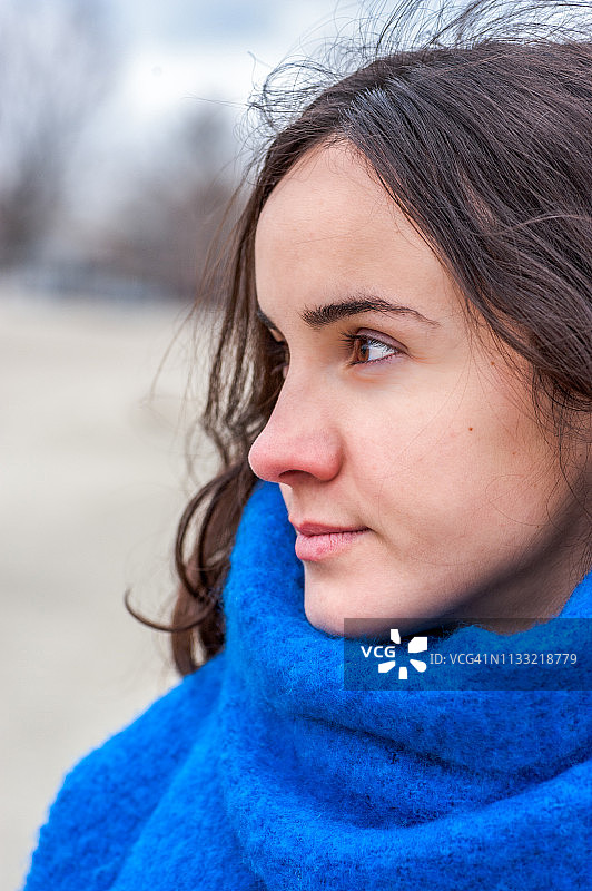 寒冷天气中佩戴蓝色围巾的年轻女孩特写人像图片素材