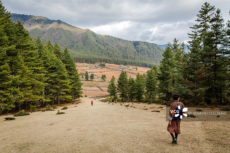 在不丹叶科，一位女游客和当地村民正在徒步下山图片素材