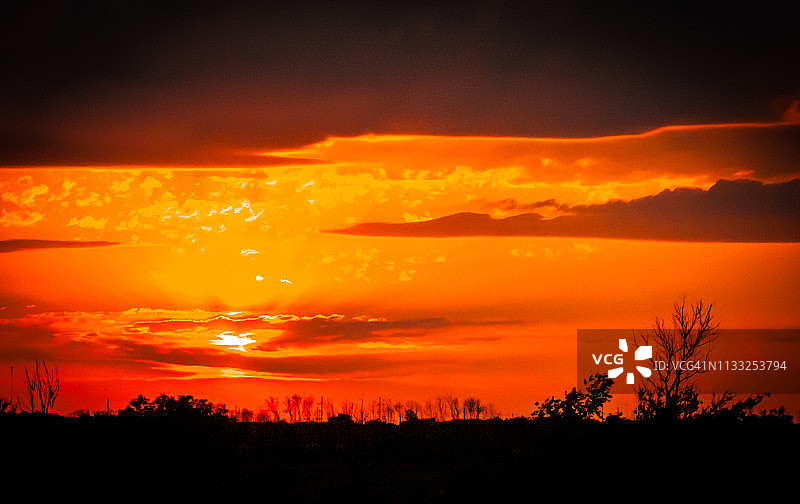 美国中西部草原上空的深红色和橙色日落图片素材