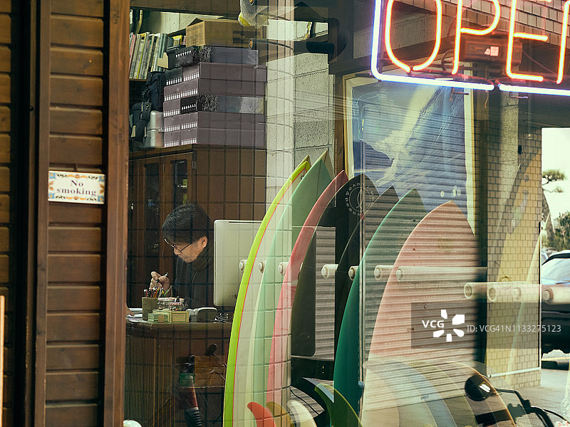 从商店橱窗外可以看到冲浪店主人的作品图片素材