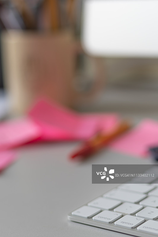 办公桌上的电脑键盘、红色钢笔、便签和笔筒图片素材