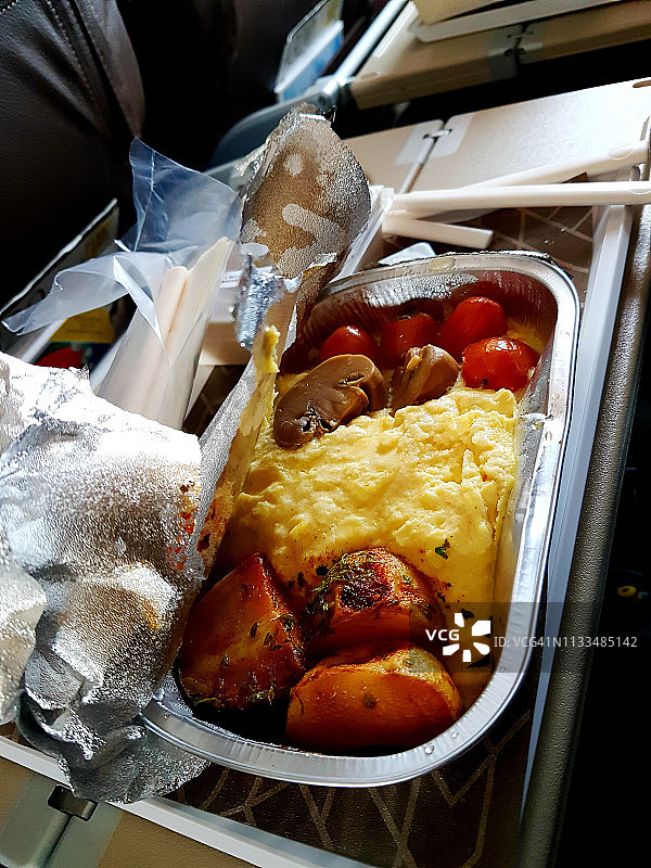 飞机餐：炒鸡蛋、烤土豆、蘑菇和番茄图片素材