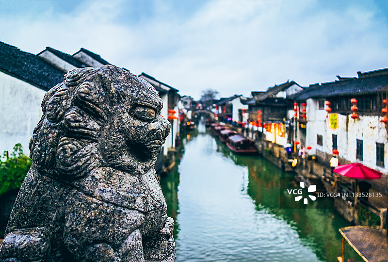 运河沿岸的古老房屋，前景有一座石狮子图片素材