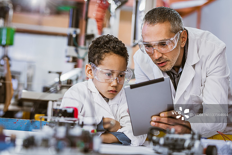 中年教师和小男孩在实验室使用平板电脑图片素材