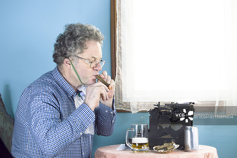 一个用旧打字机工作的人，抽着雪茄，戴着氧气面罩图片素材