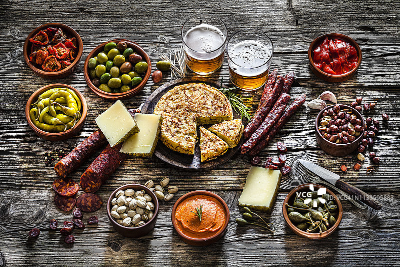 西班牙特色小吃与啤酒：乡村木桌上的美食图片素材