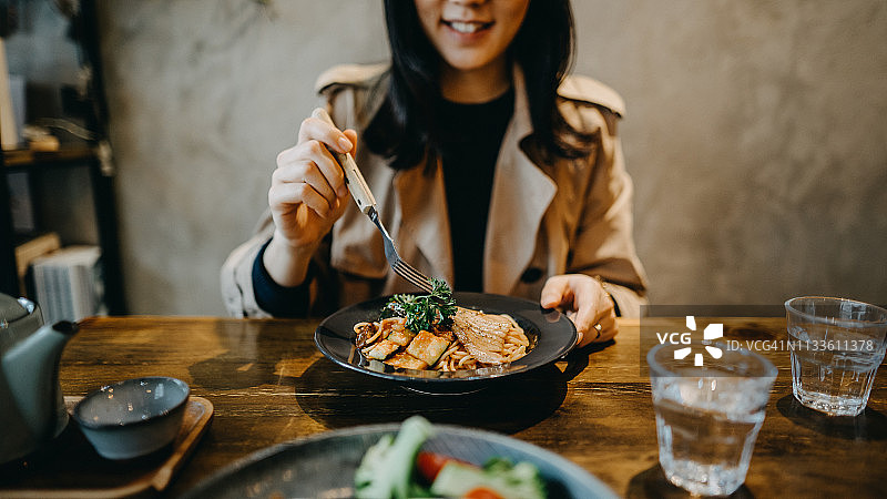 在餐厅与朋友共进晚餐的微笑年轻女子图片素材