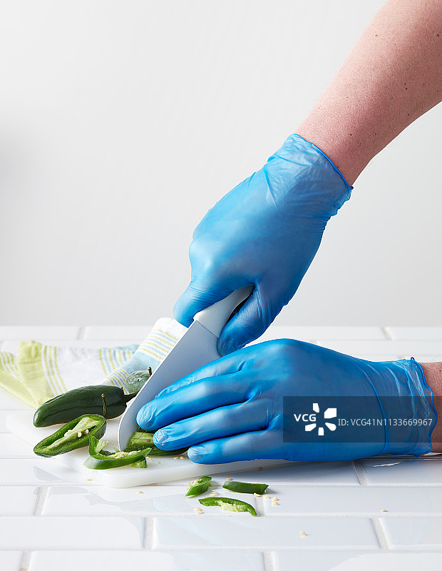 戴蓝色一次性手套切墨西哥辣椒图片素材