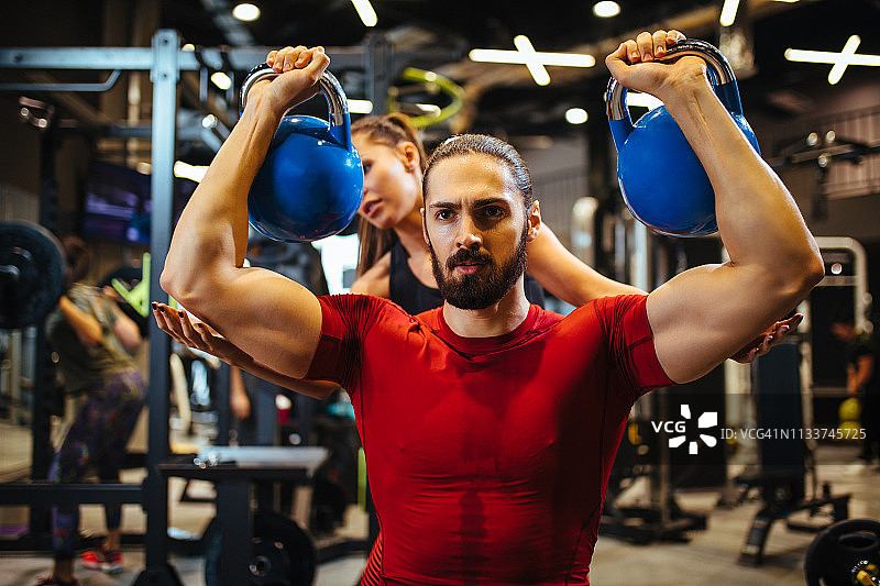 青年男子与私人教练一起进行壶铃训练图片素材