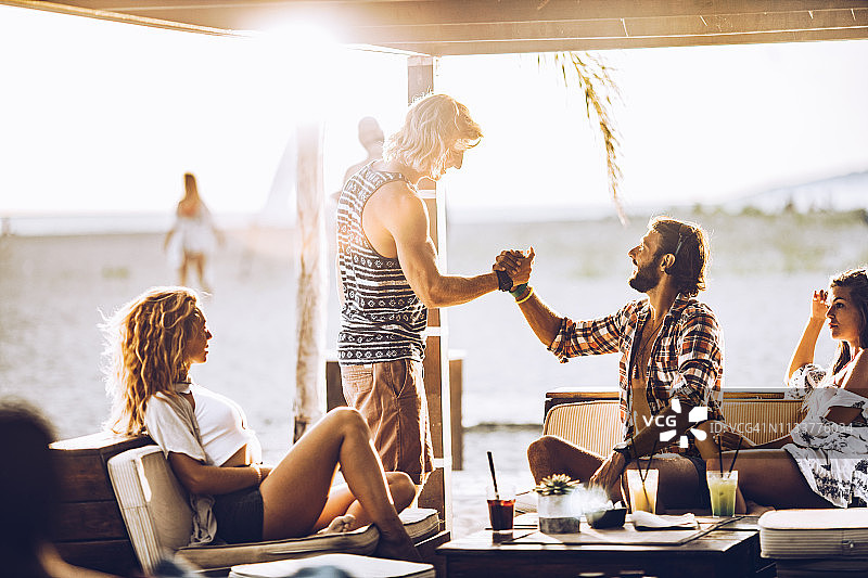 在海滩酒吧互相问候的年轻朋友图片素材