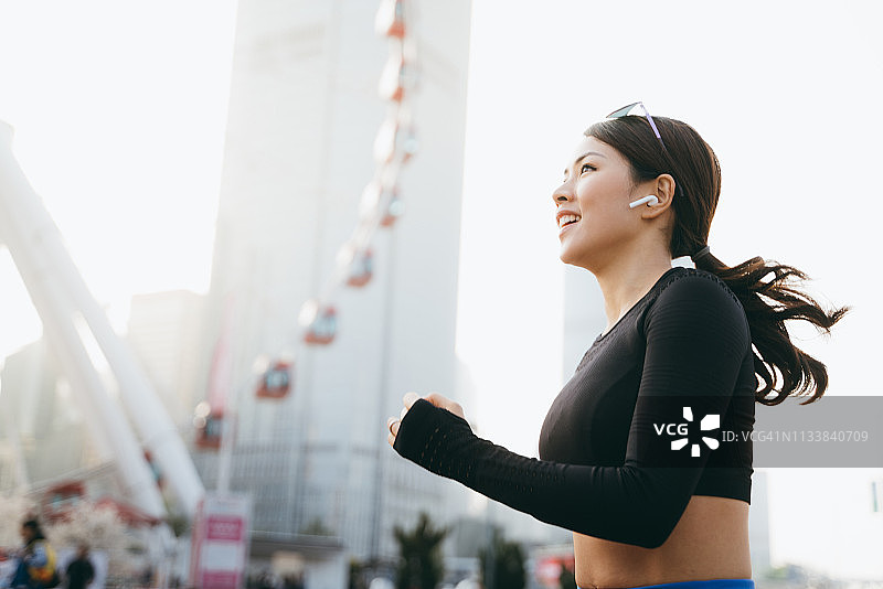 充满活力的年轻运动女性在城市慢跑时戴着入耳式耳机听音乐图片素材