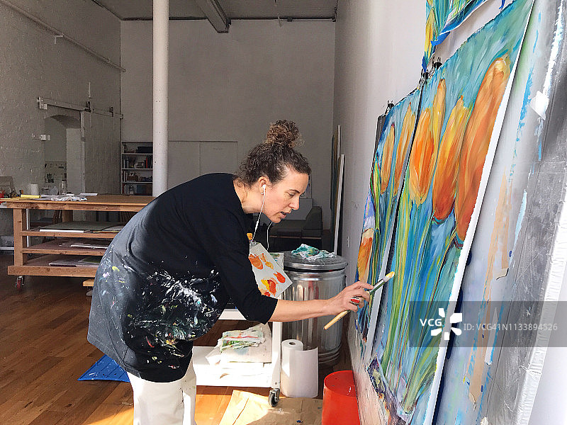 艺术家在工作室一边绘画一边用手机交谈图片素材