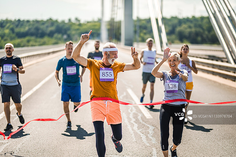 年长的马拉松选手冲过终点线庆祝胜利图片素材