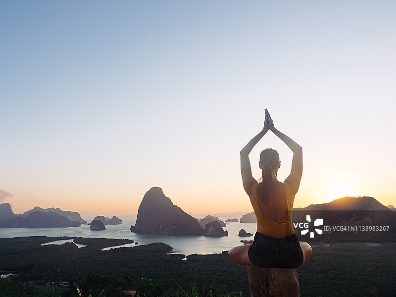 女人在著名景点攀牙湾日出时做瑜伽健身运动图片素材