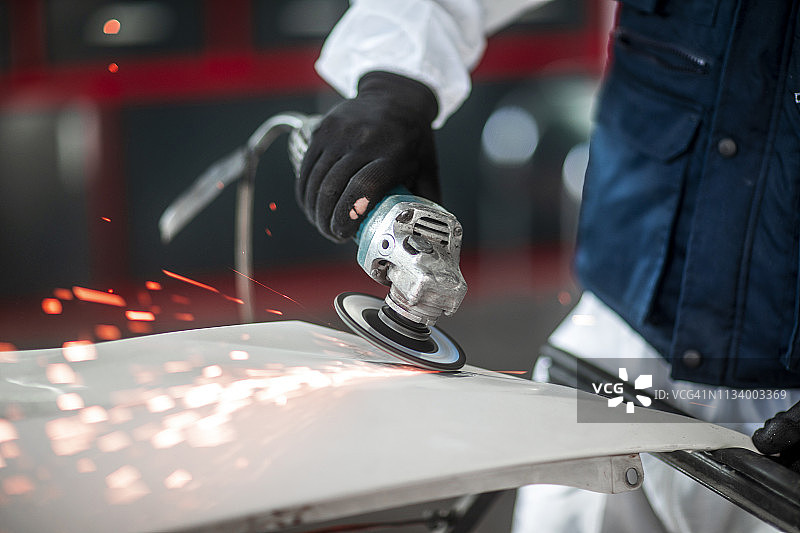 在汽车修理店使用电动研磨机研磨汽车零件图片素材
