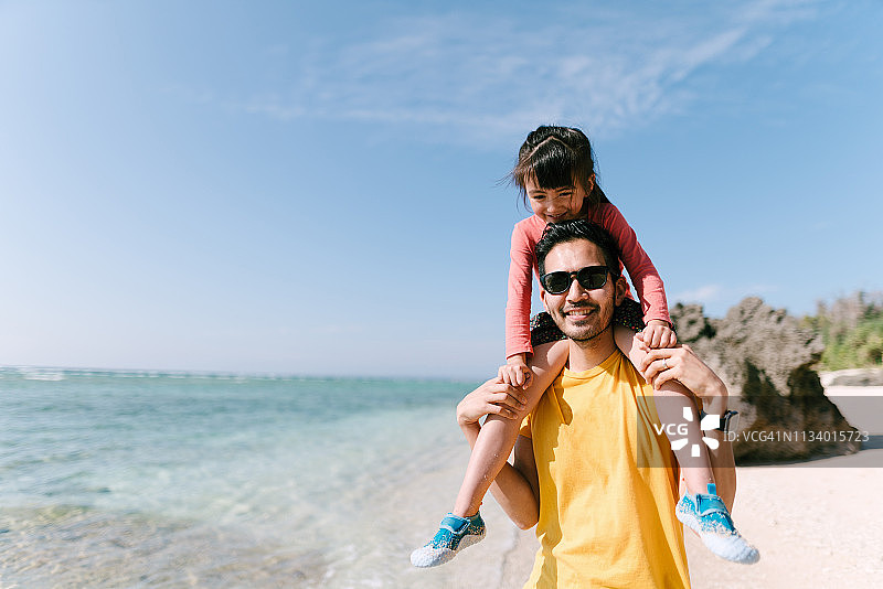 父亲在冲绳热带海滩上给小女孩骑肩，日本图片素材