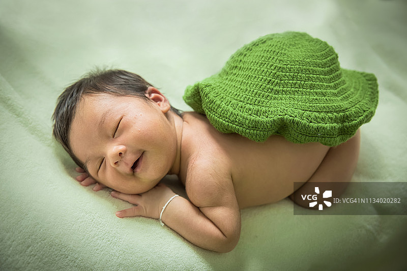 在床垫上带着微笑睡觉的可爱女宝宝图片素材