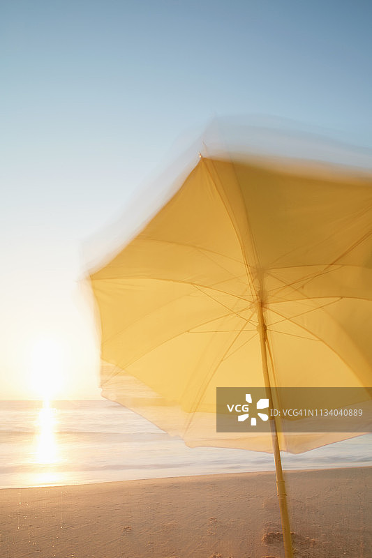 日落时分海滩上的黄色阳伞（摄影效果）图片素材