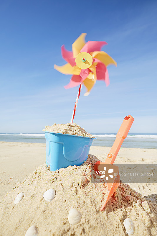 沙滩上带有彩色沙滩玩具和风车的沙堡图片素材