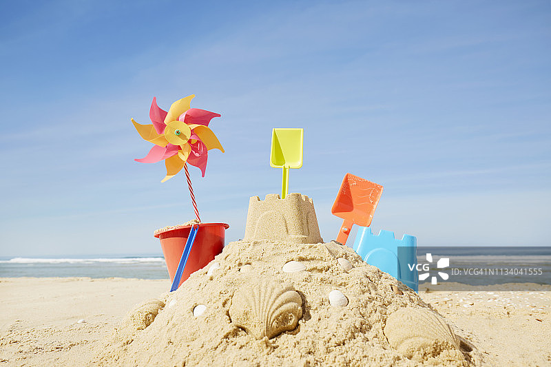 沙滩上带有彩色沙滩玩具和风车的沙堡图片素材