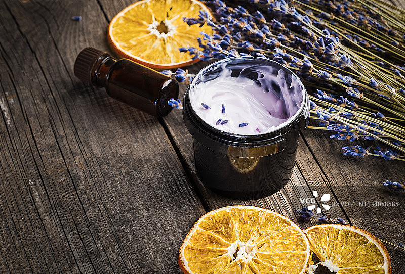 含有薰衣草和橙子干的有机保湿霜在木桌上图片素材