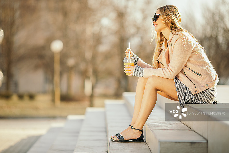 在户外休息时喝果汁的年轻女人图片素材