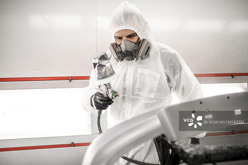 车身修理技师在喷漆房喷涂汽车部件图片素材