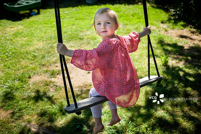 在后院的绳子上荡秋千的女孩（3岁）图片素材
