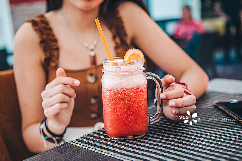 年轻游客在加那利群岛的露台上喝草莓冰沙图片素材