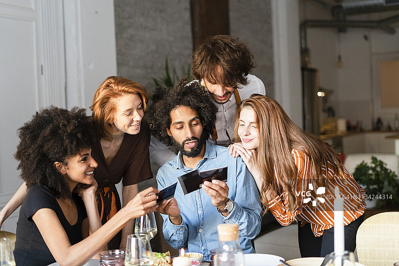 朋友们坐在餐桌旁，看着照片图片素材