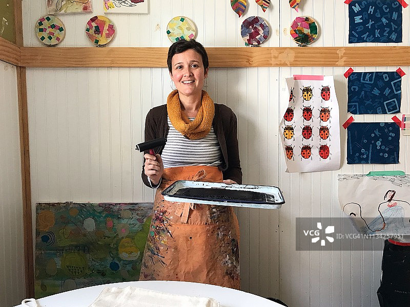 一位拿着墨水盘和滚筒进行印刷的艺术家的肖像图片素材