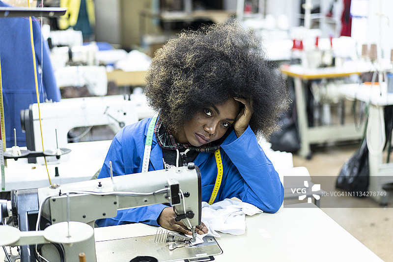 缝纫工作室内情绪低落的非裔发型年轻裁缝图片素材