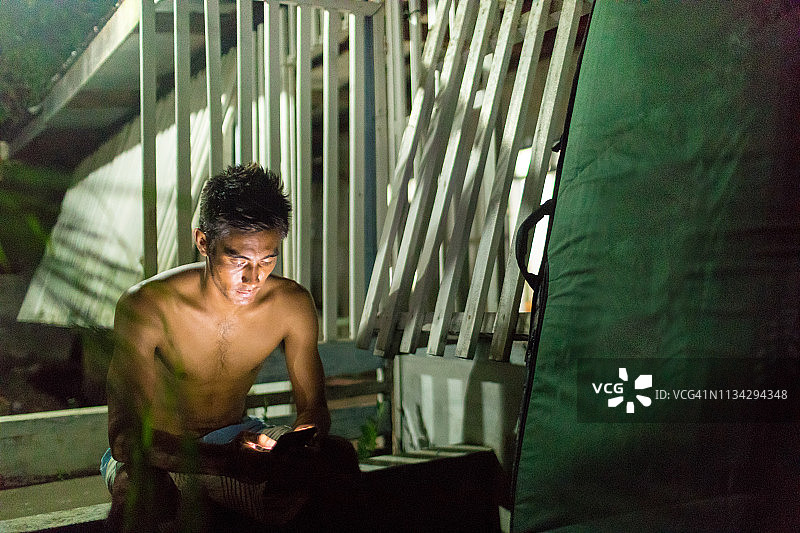 在菲律宾卡加延省阿布鲁格木制建筑旁发短信的男人图片素材