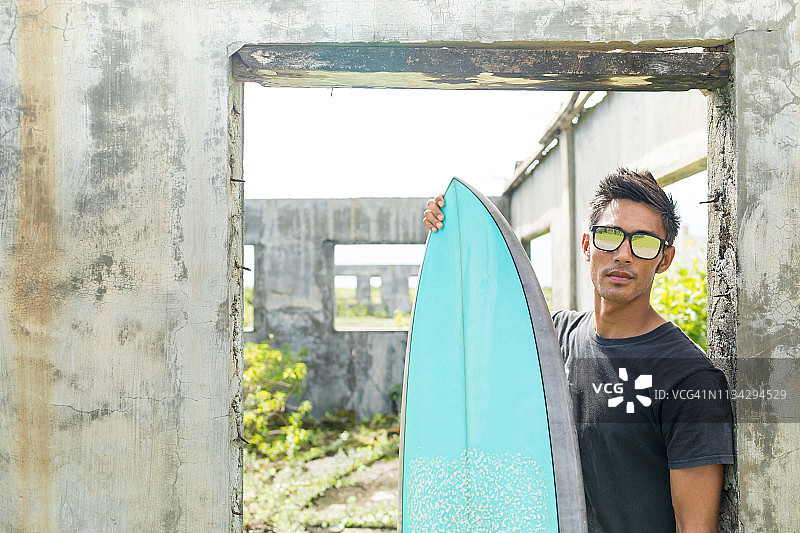 菲律宾卡加延阿布卢格废弃建筑门口的冲浪者图片素材