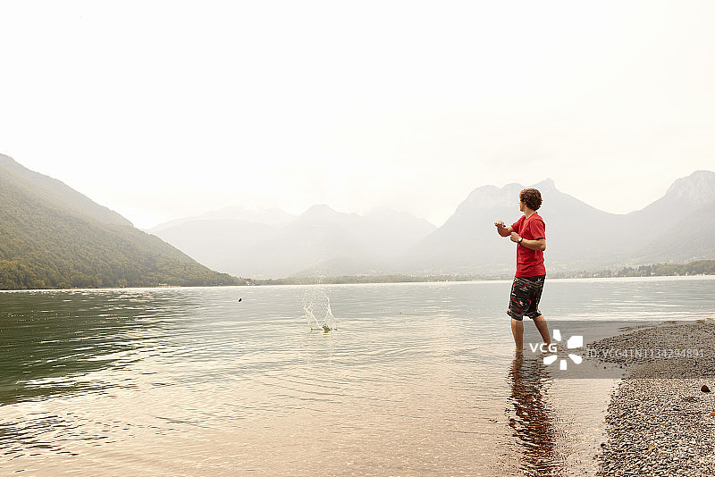 在法国罗纳-阿尔卑斯安纳西湖打水漂的年轻人图片素材