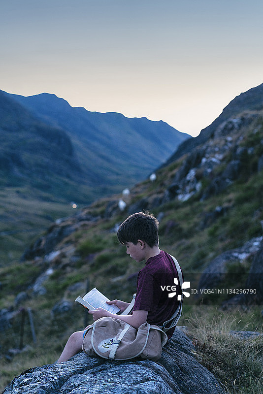 男孩在英国斯诺多尼亚山顶读书图片素材