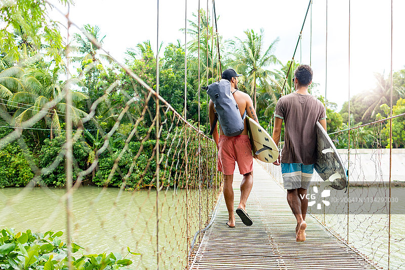 在绳索桥上拿着冲浪板的男士，位于菲律宾北伊罗戈省帕古普图片素材