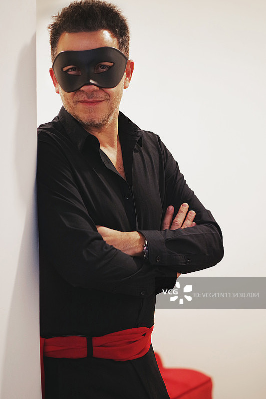 男子戴黑色面具站在白色背景前的肖像图片素材