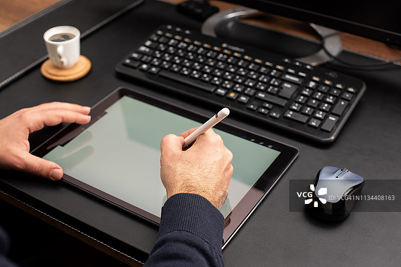 设计师在工作桌上使用手写笔在数位板上工作图片素材