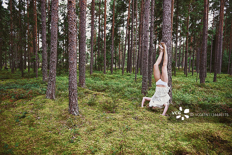 年轻女人在森林里靠着树做头倒立图片素材