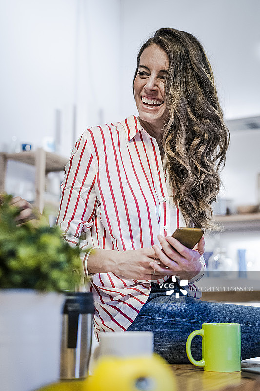 坐在桌旁玩手机的快乐女人图片素材