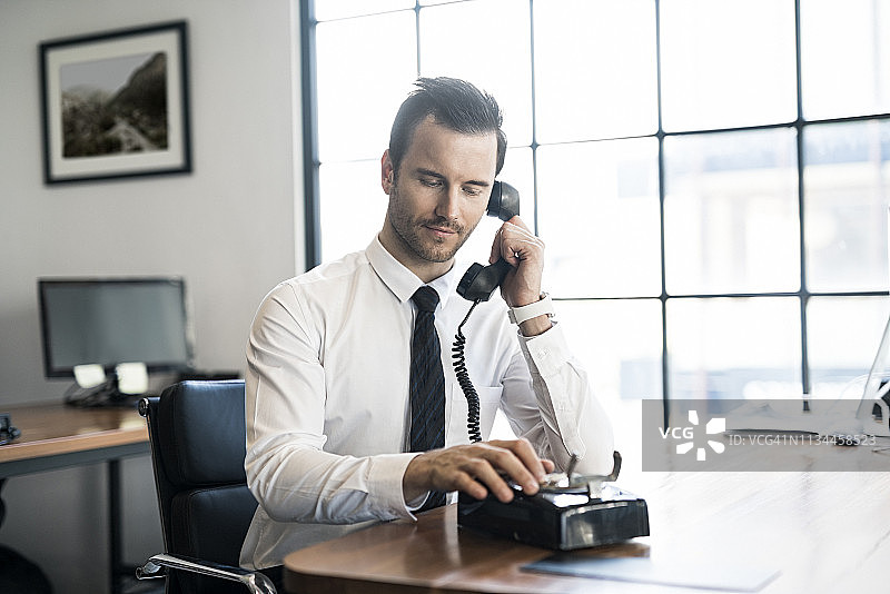 在办公室使用老式复古电话的商人图片素材