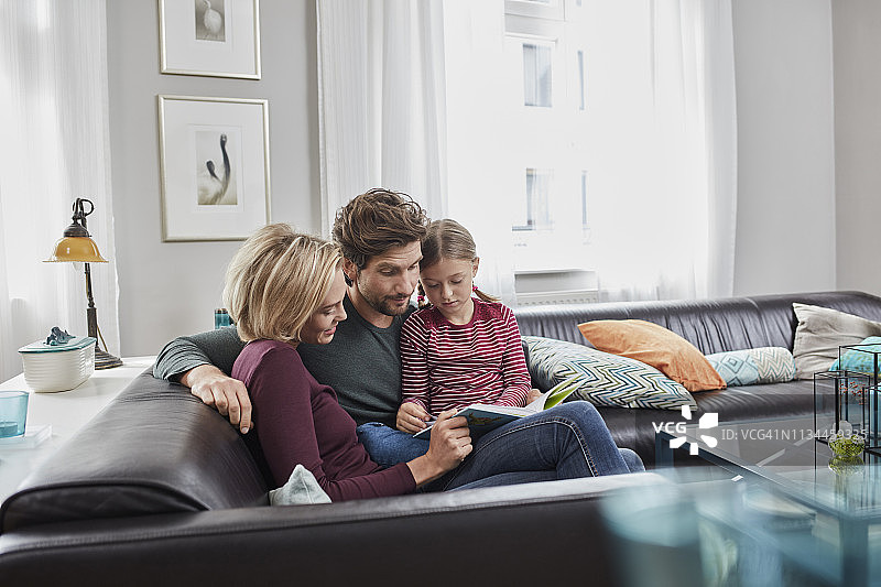 一家人坐在沙发上一起读书图片素材