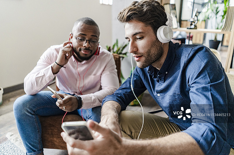 年轻男人在阁楼里向同事展示手机图片素材