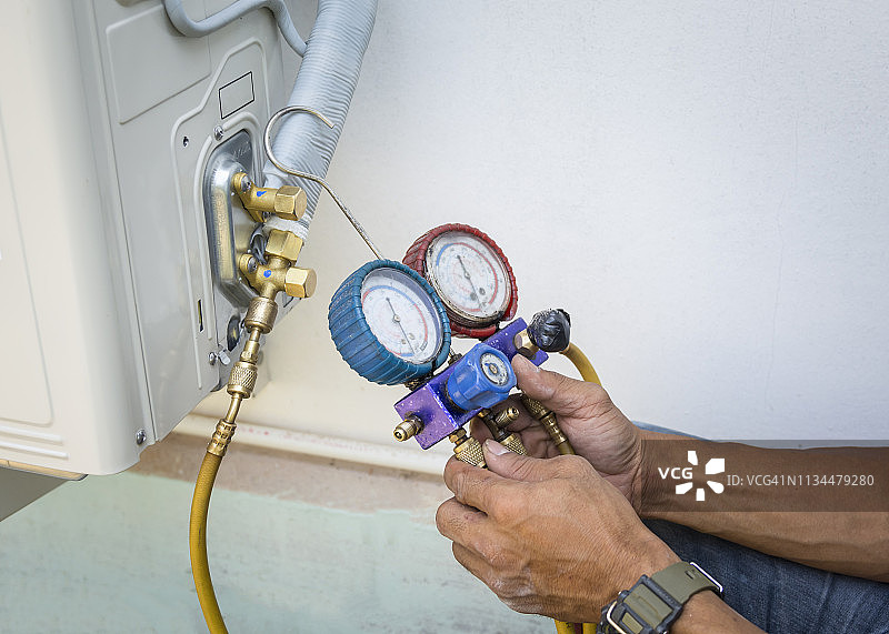 技术员用压力计检查空调设备图片素材
