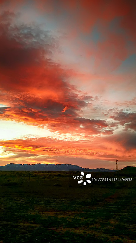 田野中间的红色和橙色日落手机照片图片素材