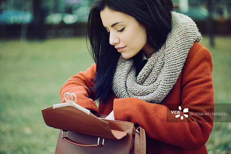 漂亮的女人在钱包里寻找东西图片素材